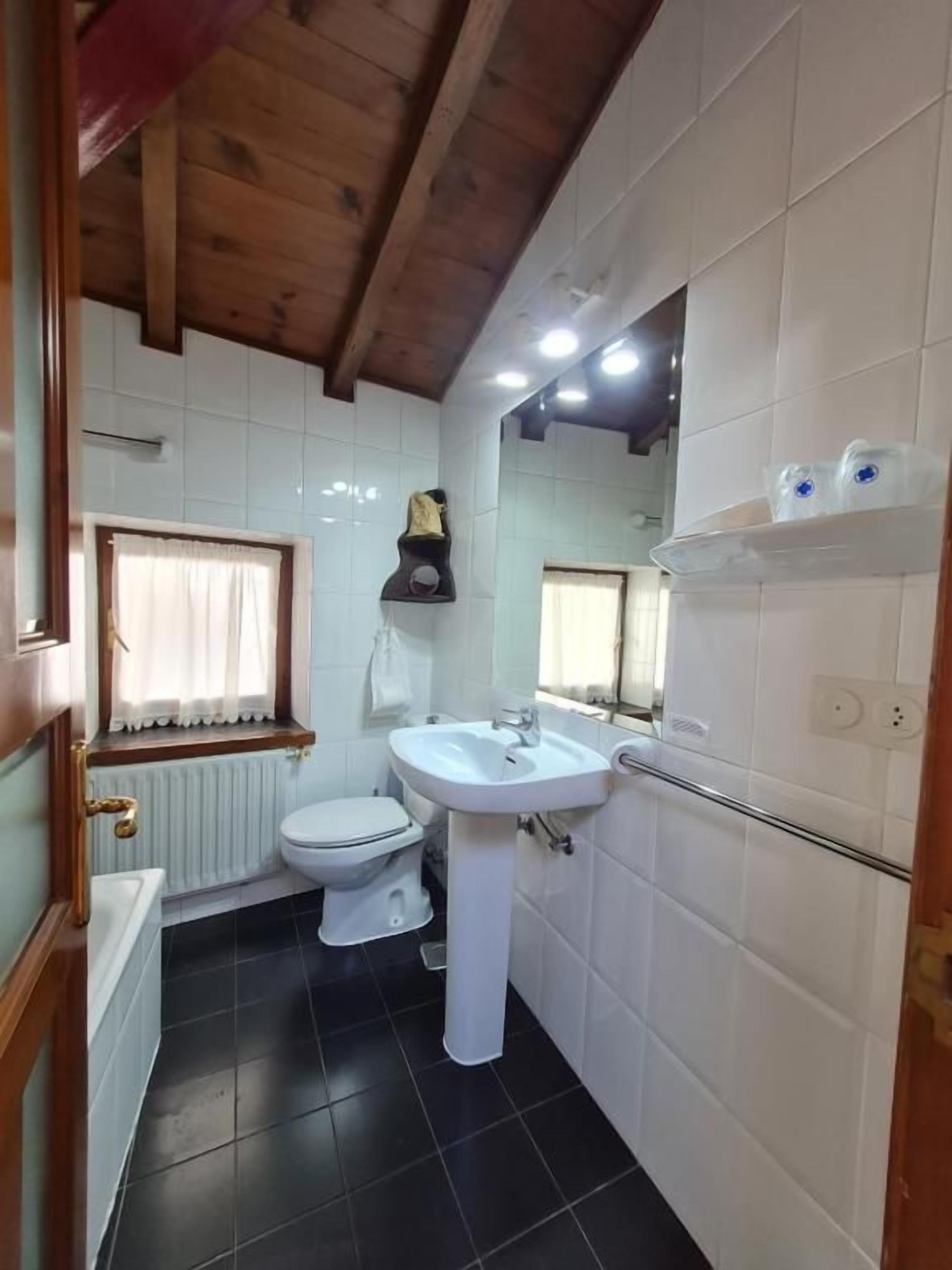 A bathroom with a toilet, sink, and mirror.