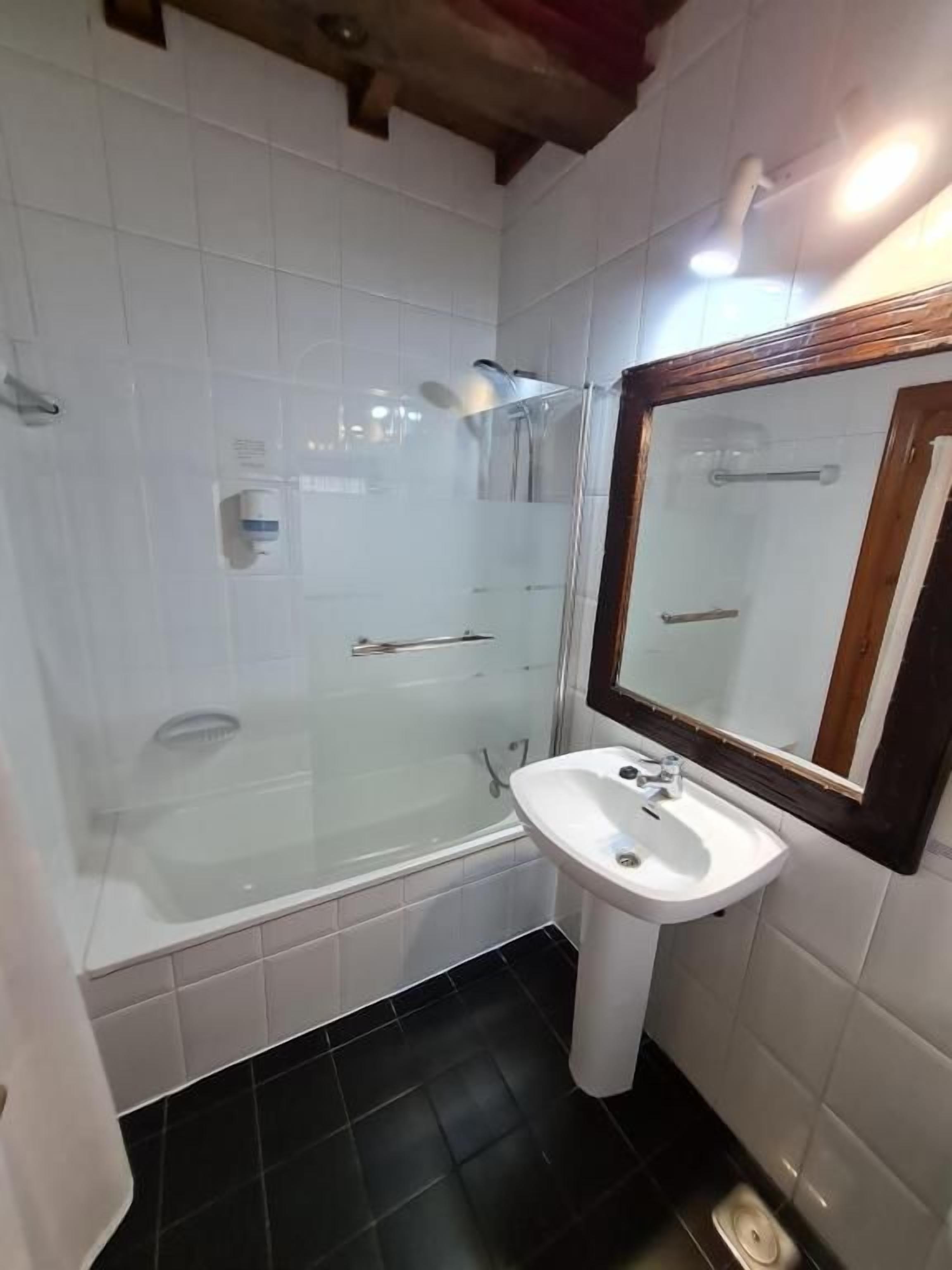 Un baño con bañera, lavamanos y espejo.