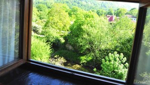 A room with a large window overlooking a forested area with a house in the distance. - La Balsa (Cangas de Onis)