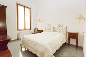 A bedroom with a bed, a nightstand, a chair, a lamp, and a window. - La Notte Blu (Florence)