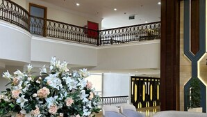 A spacious lobby with a glass coffee table, a floral centerpiece, and seating arrangements. - Dead Sea Spa Hotel (Sweimeh)