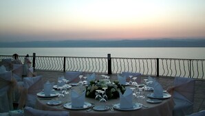 A table set for a formal outdoor event with a view of a body of water and distant mountains. - Dead Sea Spa Hotel (Sweimeh)
