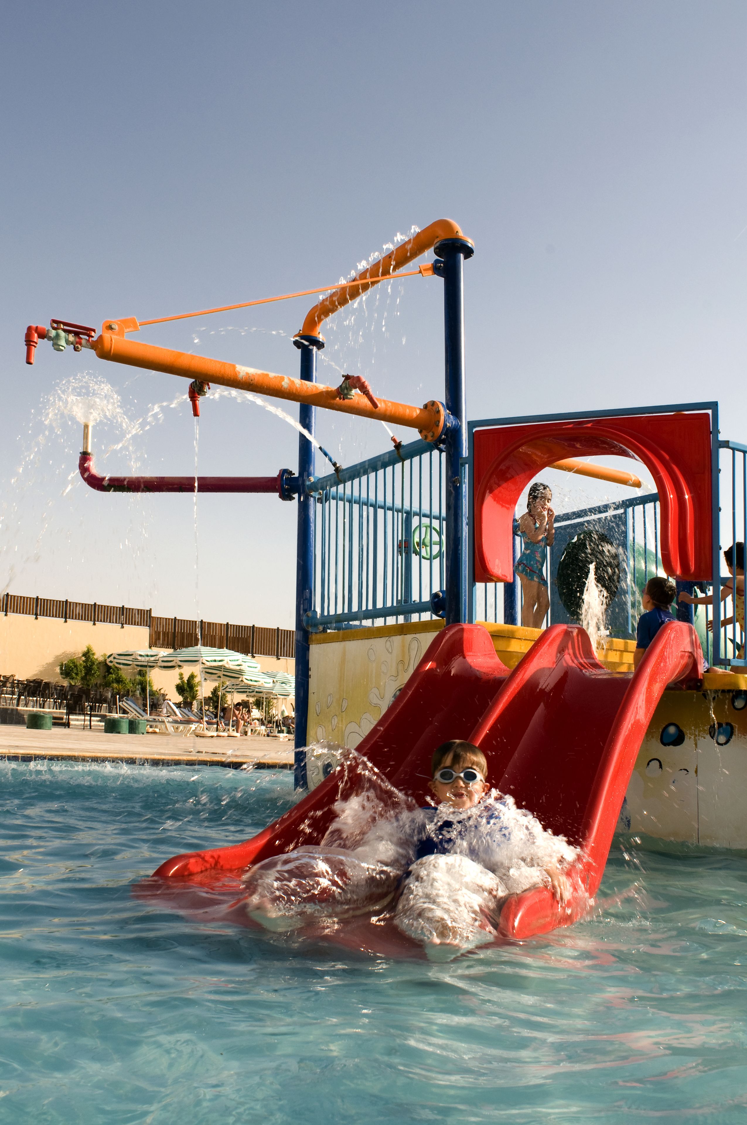 A water play area with a red slide and water jets.
