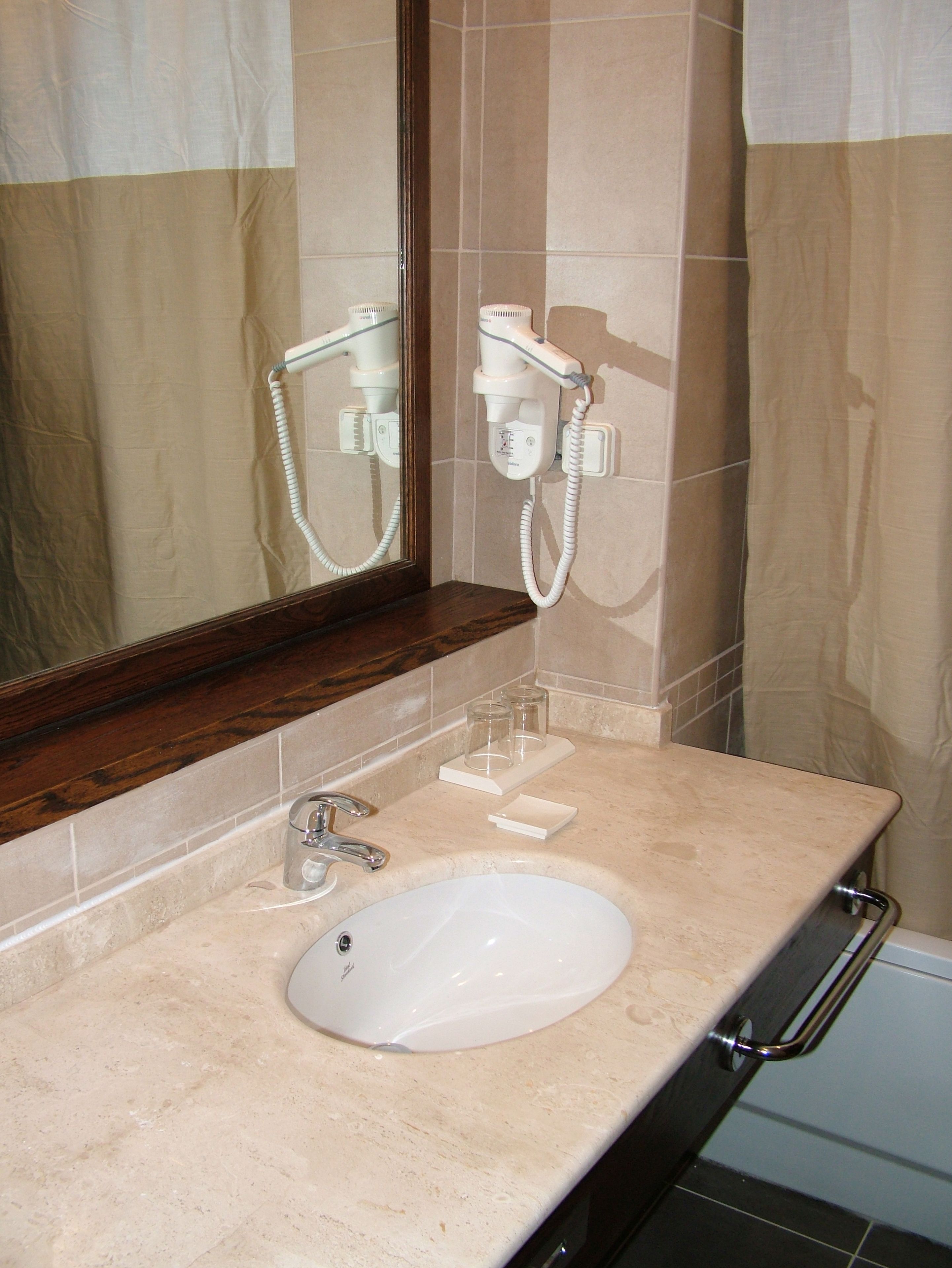 A bathroom with a sink, mirror, towel rack, and a hairdryer.