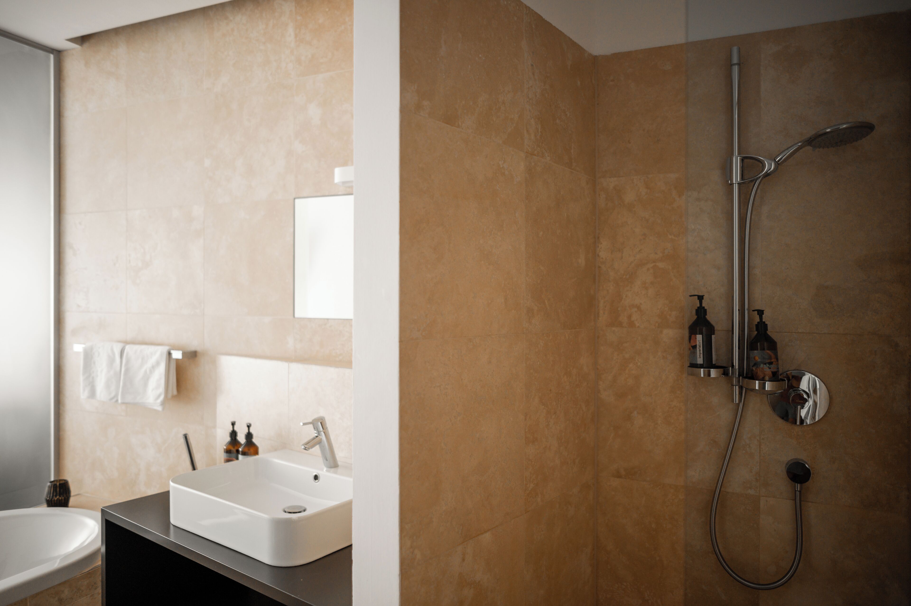 A bathroom with a bathtub, a sink, and a shower with a handheld showerhead.