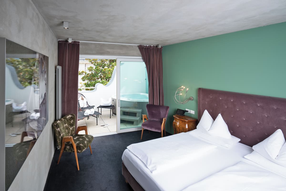 Una habitación de hotel con una cama grande, una silla, un escritorio y vistas al exterior.