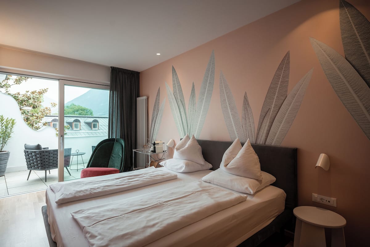 Habitación de hotel con cama, una mesita, una silla y vistas al exterior.