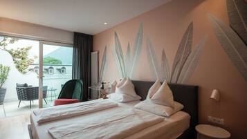 Habitación de hotel con cama, una mesita, una silla y vistas al exterior.