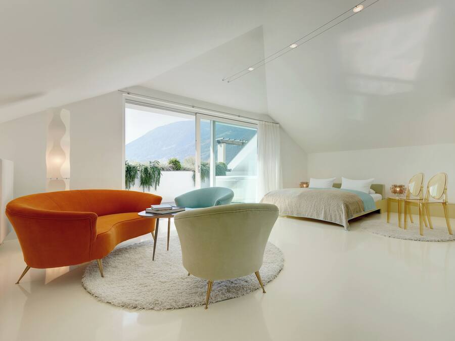 A modern bedroom with a large window, a bed, a sofa, and a chair.