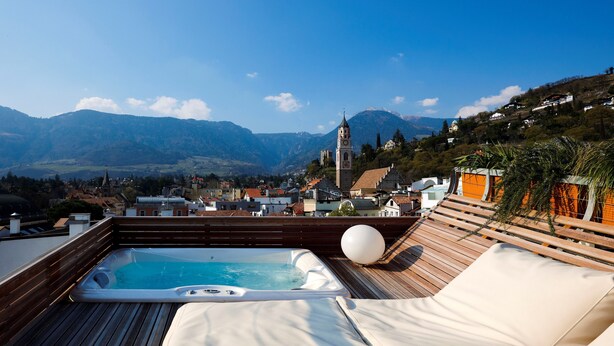 A rooftop terrace with a hot tub, lounge chairs, and a scenic mountain view. - ImperialArt (Merano)