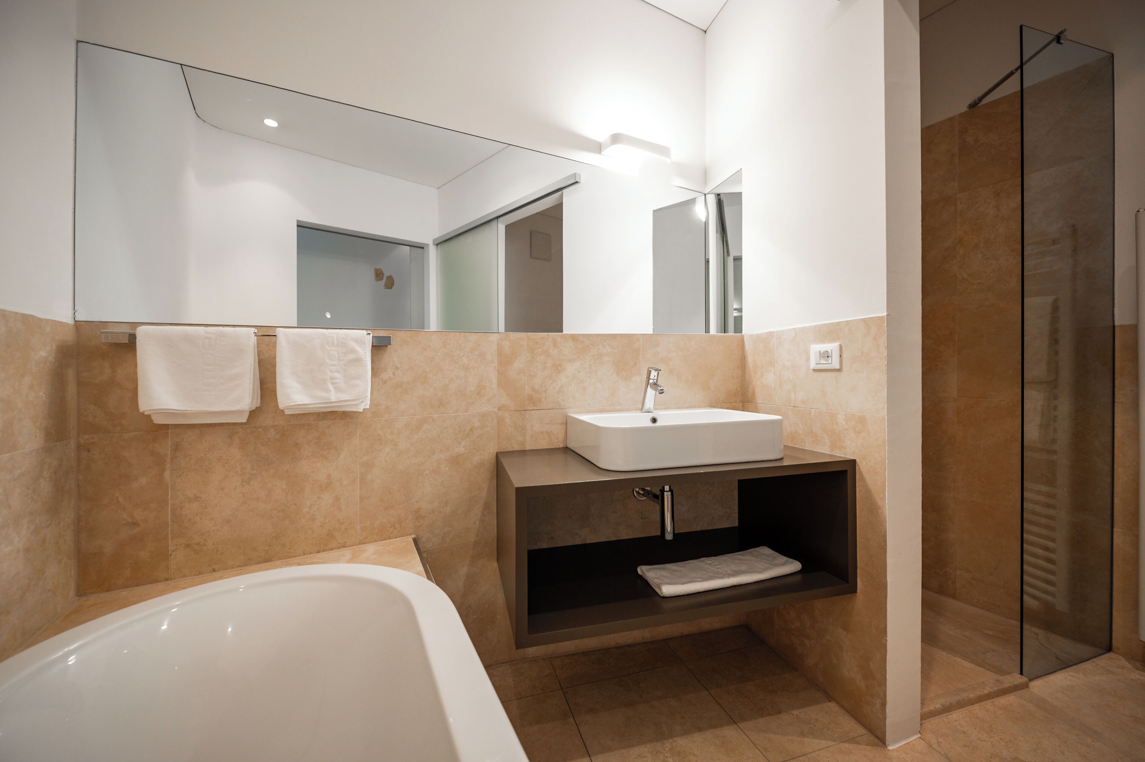 Une salle de bain moderne équipée d’une baignoire, d’un lavabo, d’un miroir et d’un espace douche.