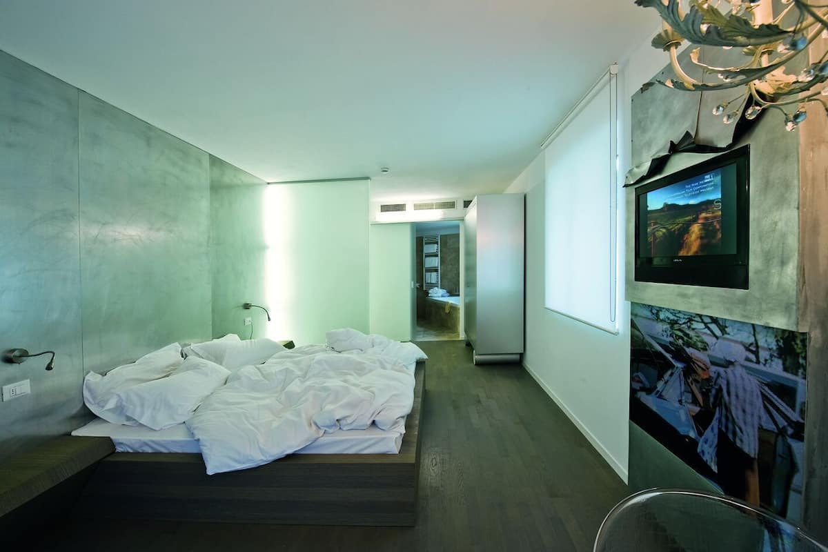 Un dormitorio moderno con cama, televisor y un pasillo que da a un baño.