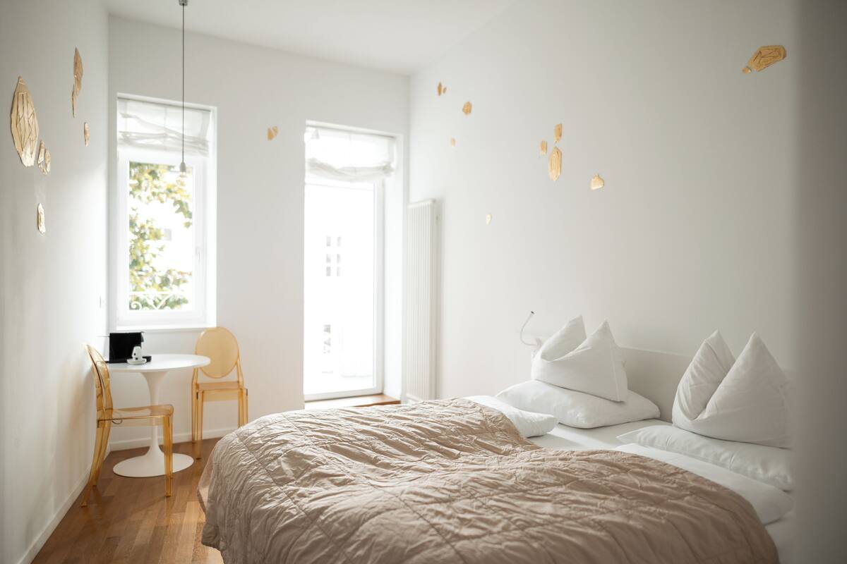 Un dormitorio minimalista con cama, mesita de noche y ventana con vistas al verdor.