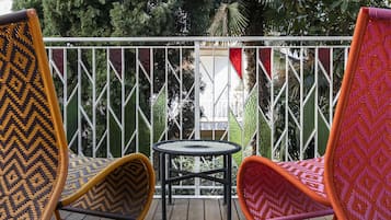 A balcony with two wicker chairs and a small round table.