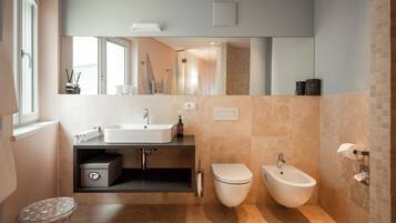 A modern bathroom with a large mirror, a sink, a toilet, and a bidet.