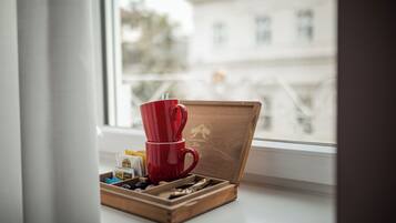 A wooden box with a red cup and tea bags on a windowsill.
