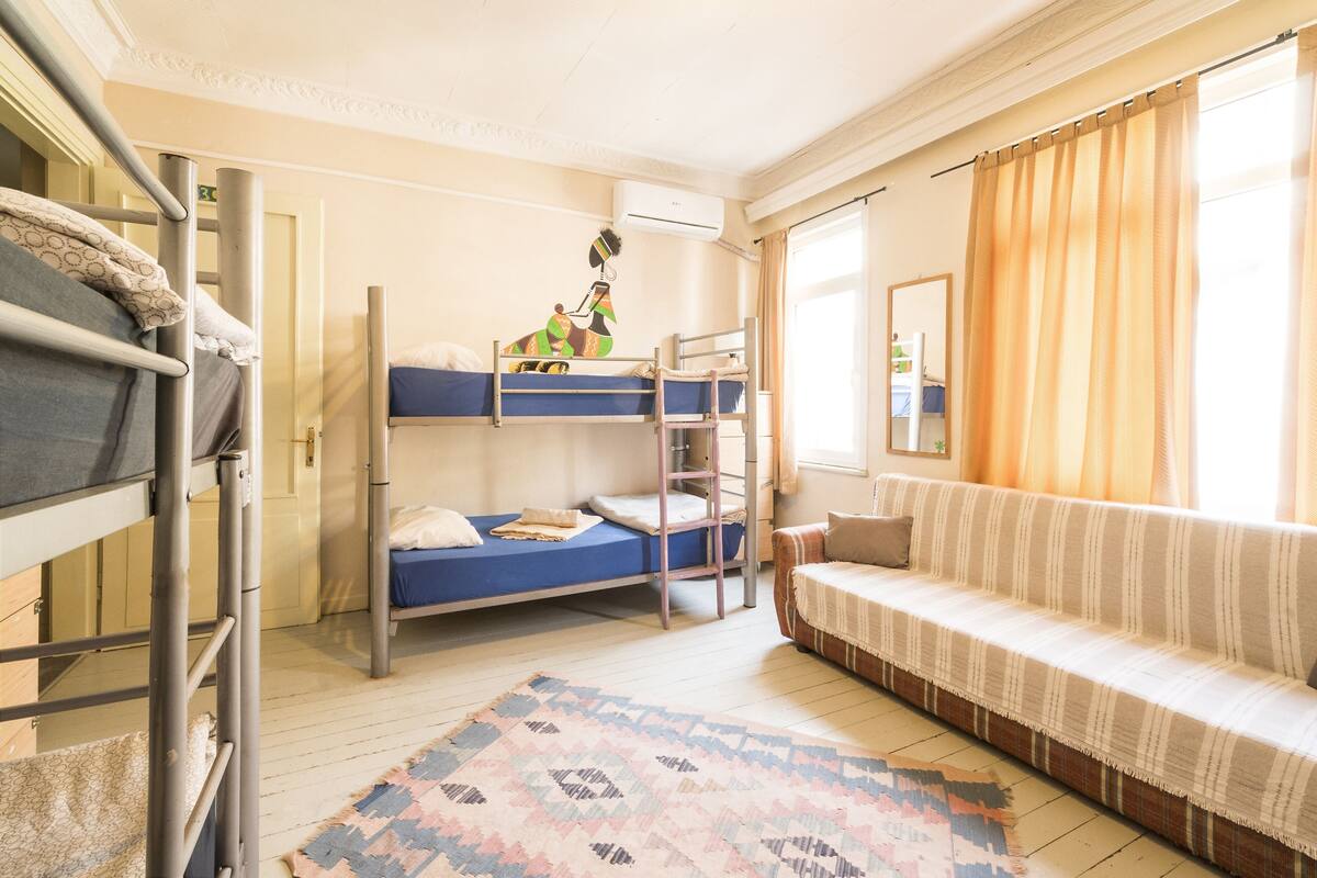 Une chambre de dortoir avec des lits superposés, un canapé et un tapis à motifs.