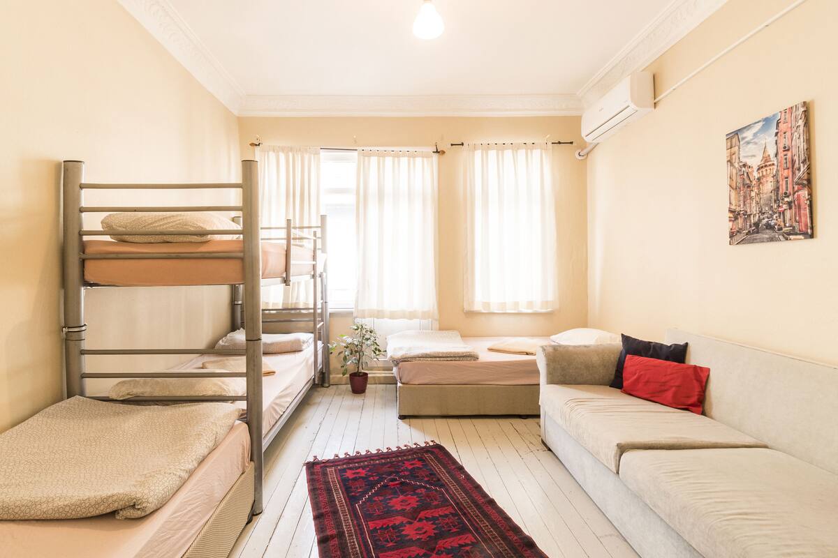 Une chambre de dortoir avec des lits superposés, un canapé, une table basse et un tableau accroché au mur.