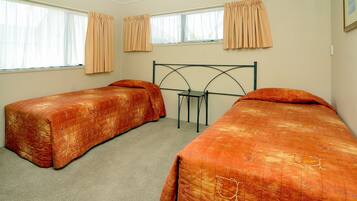 A bedroom with two single beds, a nightstand, and a window with curtains.