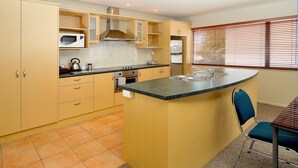 A kitchen with a central island, a microwave, and a stove. - Academy at Botany Motor Inn (Auckland)