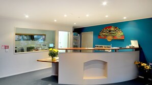 A reception desk with a modern design, a large window, and a wall-mounted artwork. - Academy at Botany Motor Inn (Auckland)