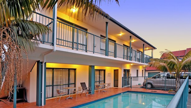 A hotel with a pool, outdoor seating, and a carport. - Academy at Botany Motor Inn (Auckland)