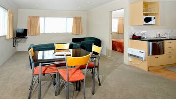A compact hotel room with a dining area, kitchenette, and a TV.