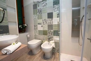 A bathroom with a large sink, toilet, bidet, and a shower area. - Hotel Alassio (Montecatini Terme)