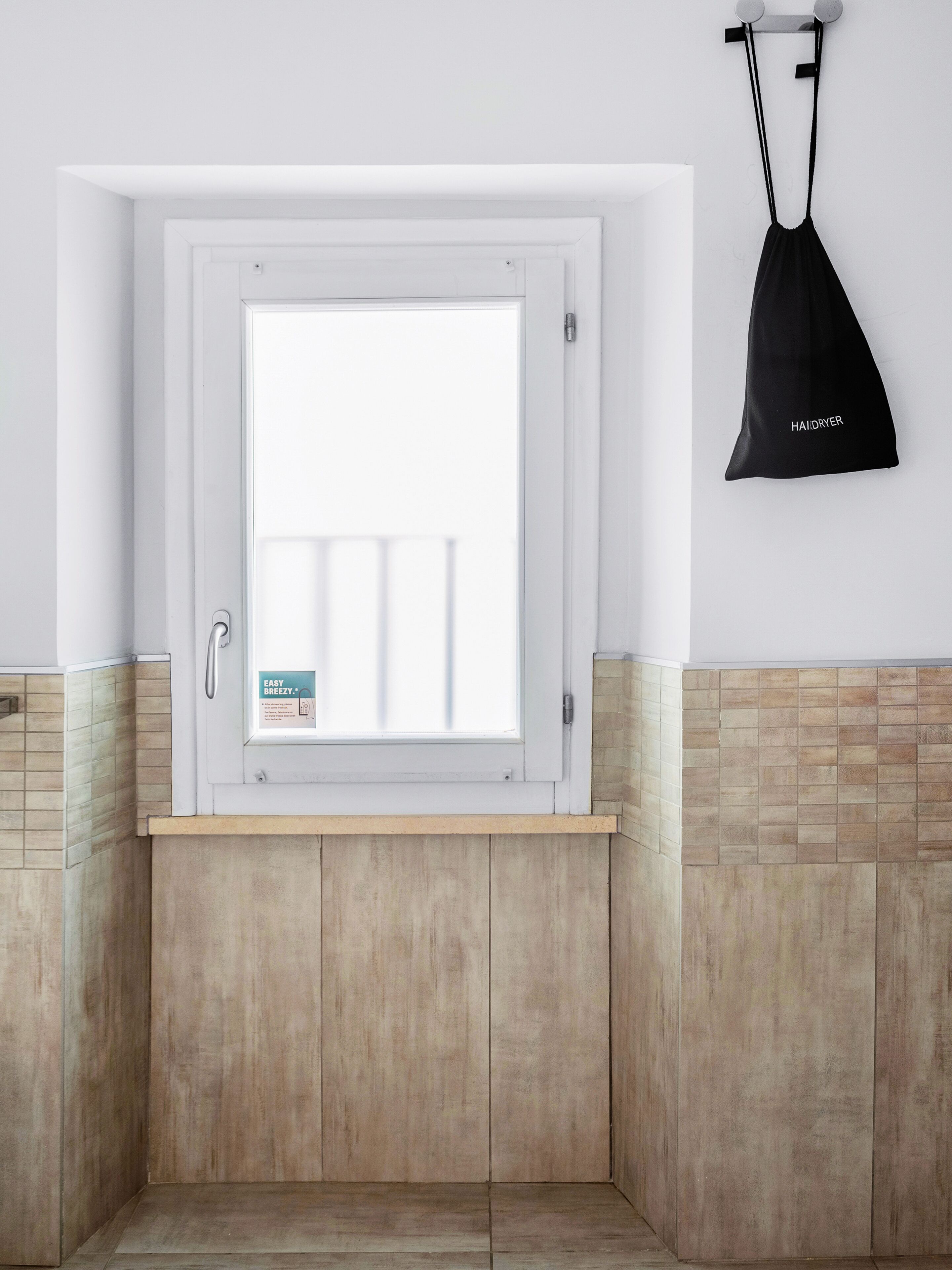 A bathroom with a window, a towel rack, and a tiled floor.