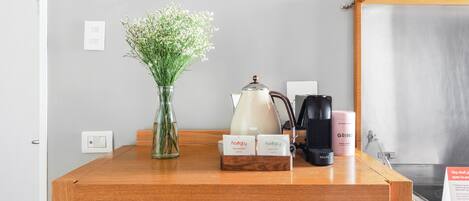 Un comptoir en bois orné d’un vase de fleurs, d’une machine à café, d’une bouilloire et d’une enseigne.