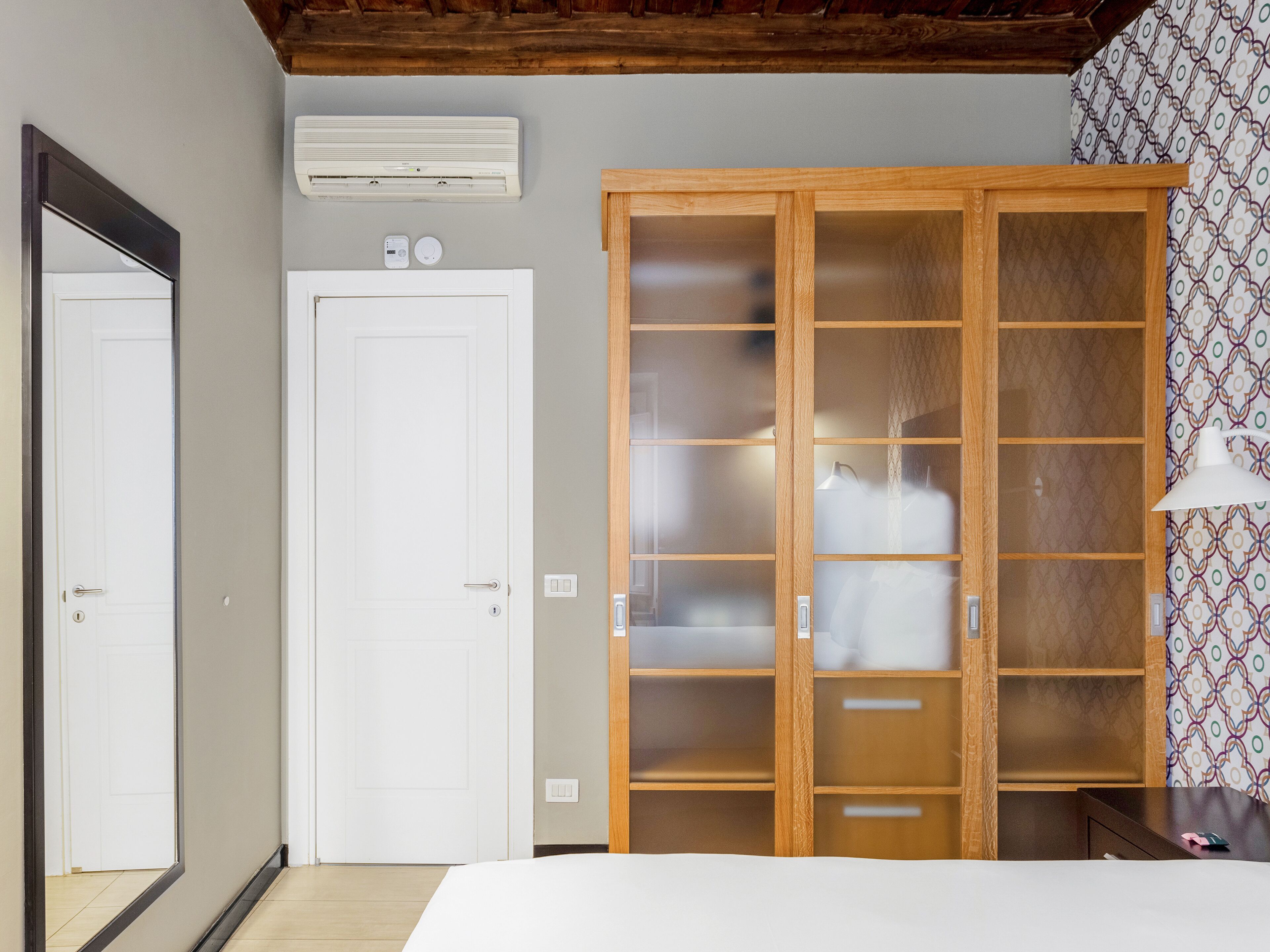 Ein Schlafzimmer mit einem Holzschrank, einer weißen Tür und einer Wand mit Muster.