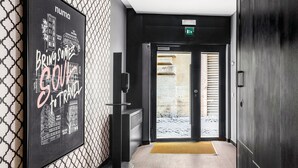 A modern hotel lobby with a large blackboard displaying travel destinations, a reception desk, and a view of the outside. - Numa Rome Vici (Rome)