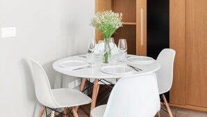 A dining area with a round table set for four, surrounded by white chairs with wooden legs. A vase with white flowers is placed on the table. - Numa Rome Vici (Rome)