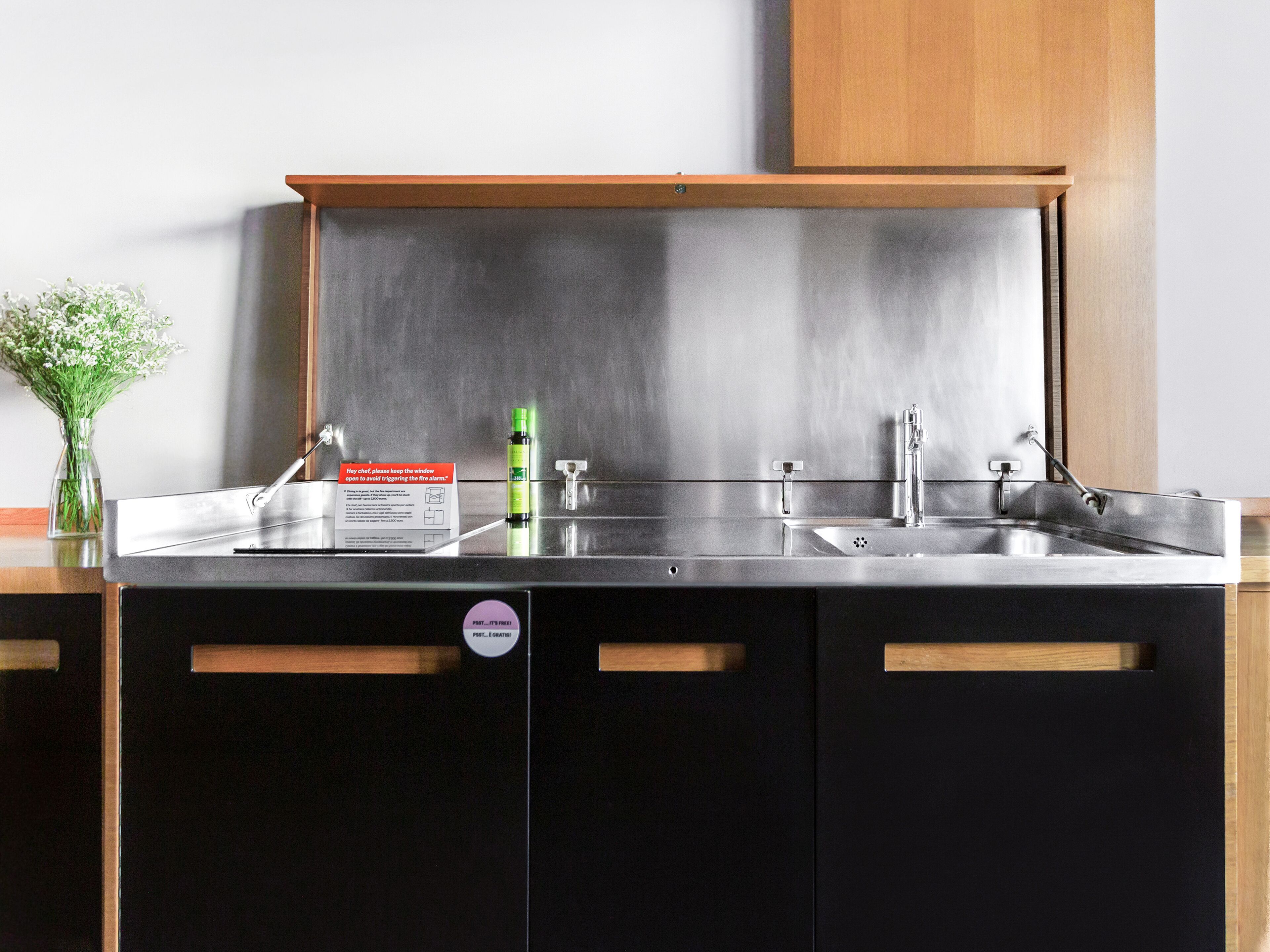 A modern kitchen with a stainless steel countertop, a sink, and a cabinet with a wooden handle.