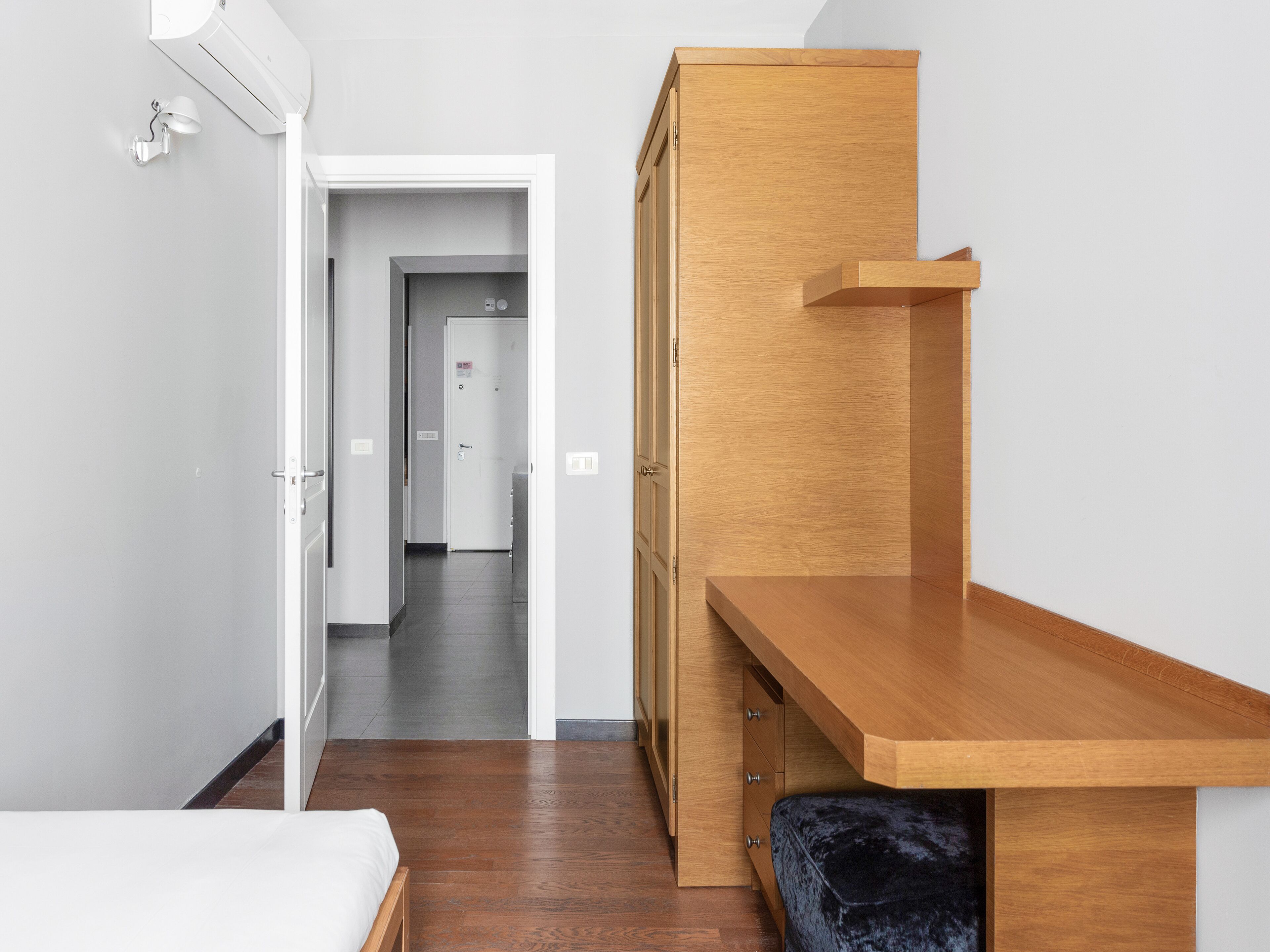 A bedroom with a wooden desk, a bed, and a wardrobe.