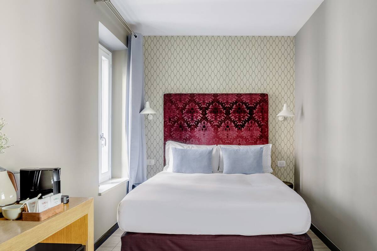 Une chambre d’hôtel avec un lit, un bureau doté d’une machine à café et une fenêtre avec des rideaux.