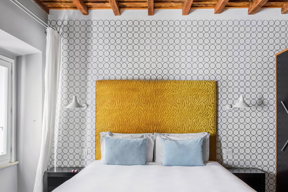 Une chambre à coucher avec un lit, une tête de lit et un mur décoré d’un motif.