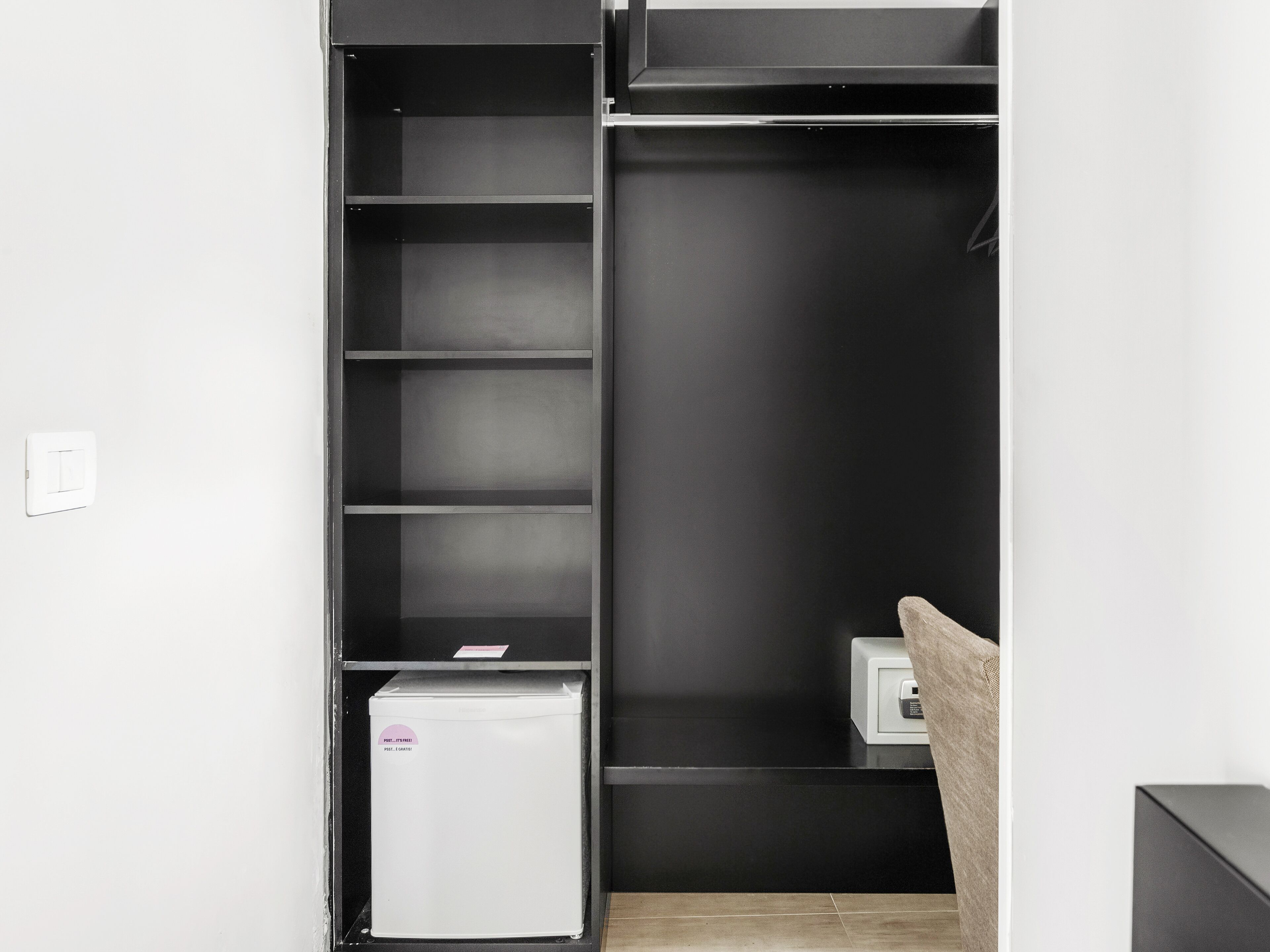 Un armario compacto y moderno con varios estantes y un refrigerador pequeño.