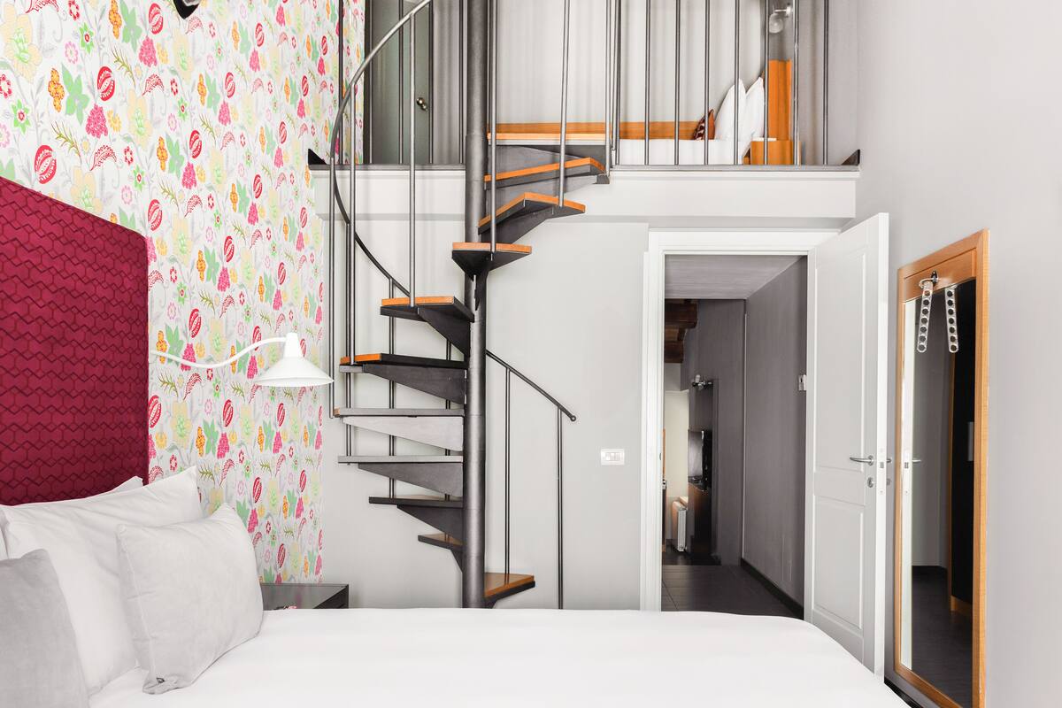 Une chambre moderne avec un escalier, un lit et une vue sur un couloir.