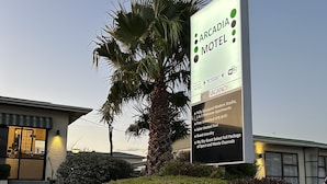 Skilt for Arcadia Motel, der reklamerer med fuldt udstyrede, moderne studielejligheder, 1- og 2-værelseslejligheder, gratis ubegrænset UFB WiFi, solvarme swimmingpool, vaskeri for gæster og et udvalgt pakke med sports- og filmkanaler.