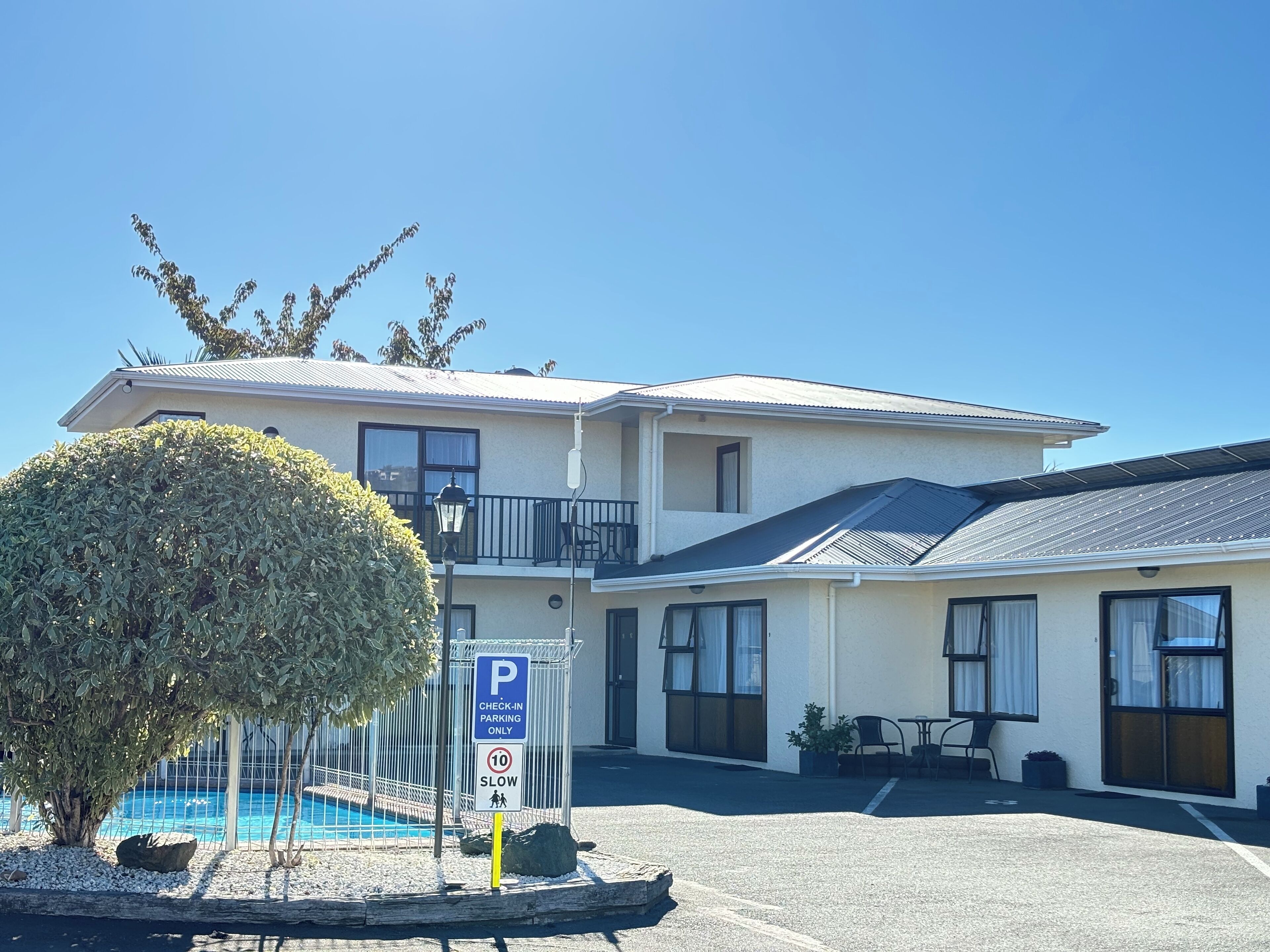 A two-story motel with a pool, check-in parking, and a balcony.
