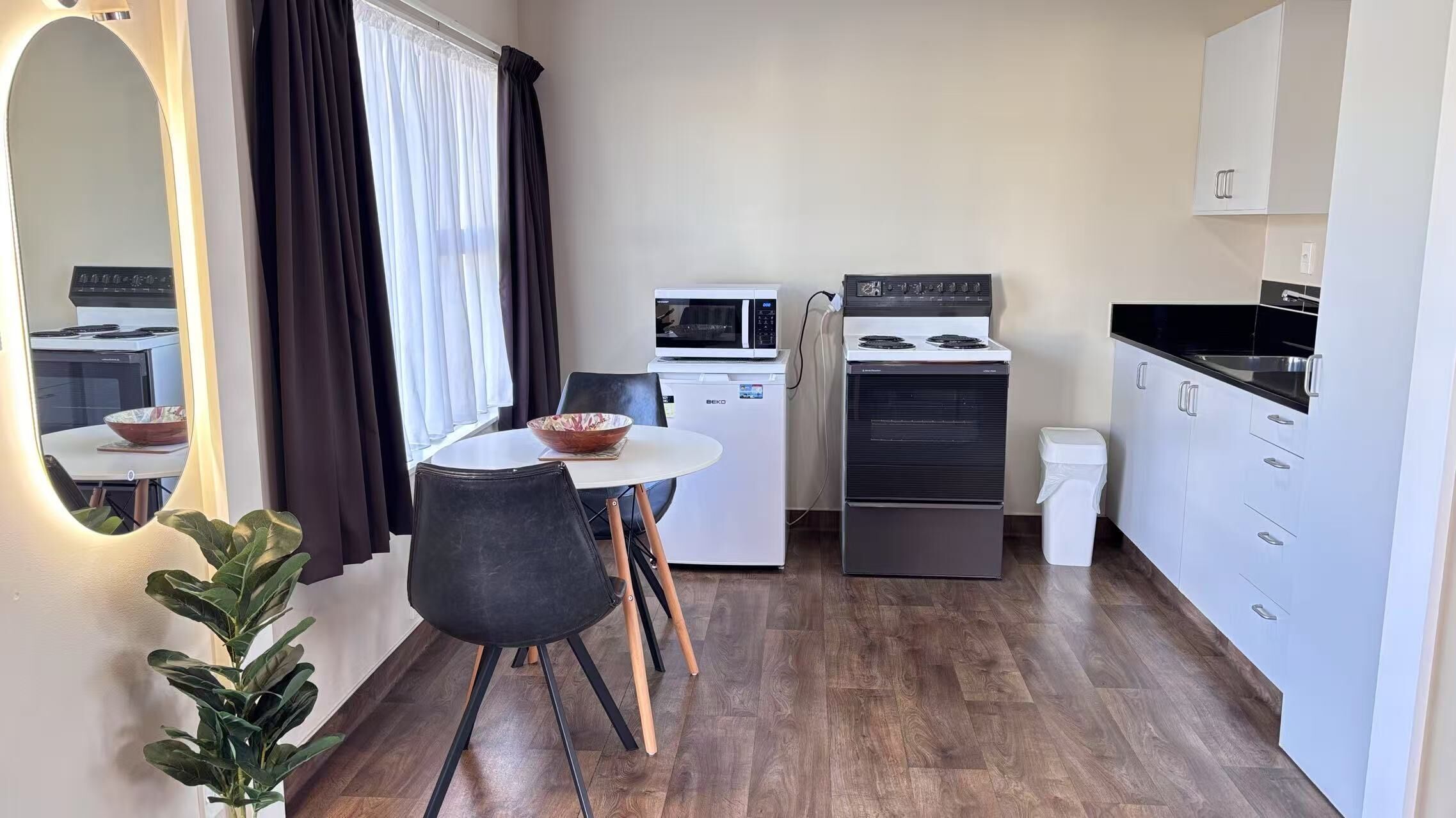 A compact kitchen with a dining area, a microwave, a stove, and a refrigerator.