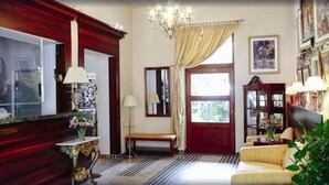 A reception area with a wooden reception desk, a bench, a chandelier, and a sofa. - Aparthotel Miodosytnia (Kraków)