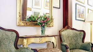 A room with two green upholstered armchairs, a matching ottoman, and a gold-framed mirror on the wall. - Aparthotel Miodosytnia (Kraków)