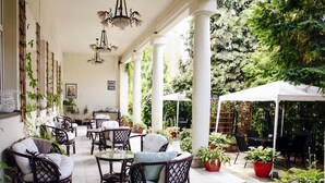 An outdoor patio area with wicker furniture, potted plants, and a white canopy. - Aparthotel Miodosytnia (Kraków)
