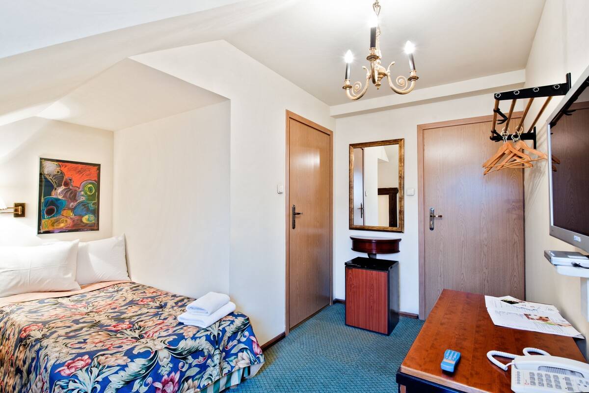 Una habitación de hotel con cama, escritorio, espejo, televisión y baño.