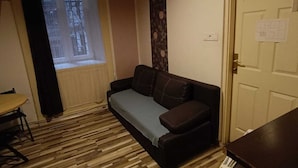 A cozy room with a wooden ceiling, a sofa, a small table, and a window with a view of a building.