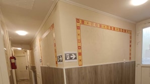 A hallway with a patterned wooden floor, a white wall with a decorative border, and a ceiling with recessed lighting.