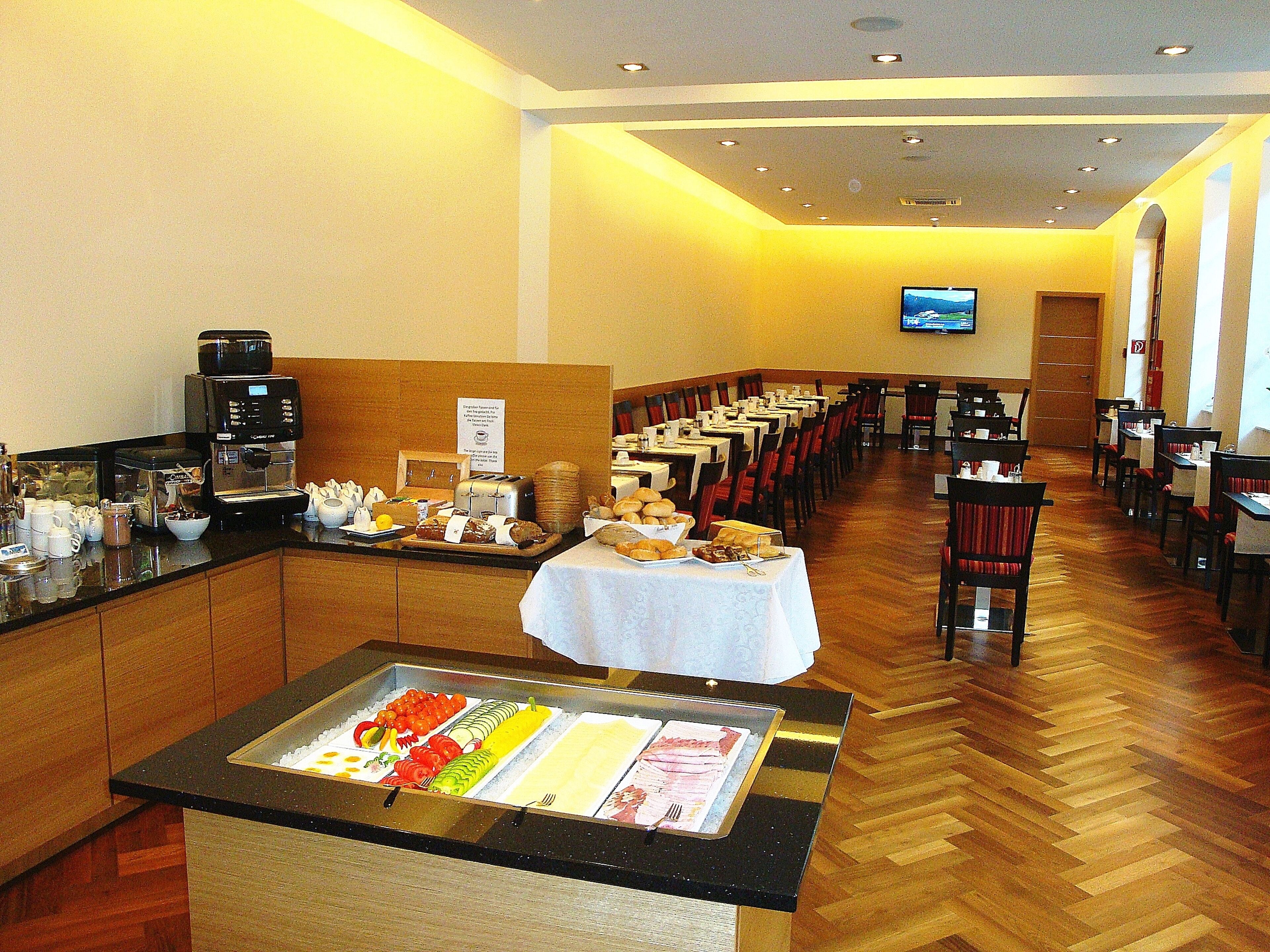 A buffet setup with various food items and a coffee station in a dining area with tables and chairs.