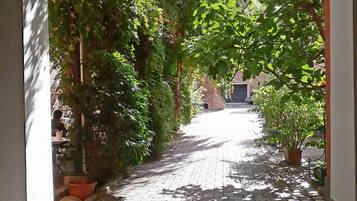 Un camino arqueado que conduce a un edificio, rodeado de vegetación y muros de ladrillo.